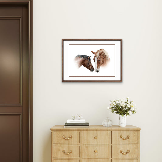 Buntstiftzeichnung zweier Pferdeköpfe, eins braun mit schwarzer Mähne, eins fuchsfarben mit heller Mähne, die sich an der Nase beschnuppern, mit braunem Rahmen gerahmt an der Wand über einer hellen Kommode, rechts neben einer braunen Tür.
