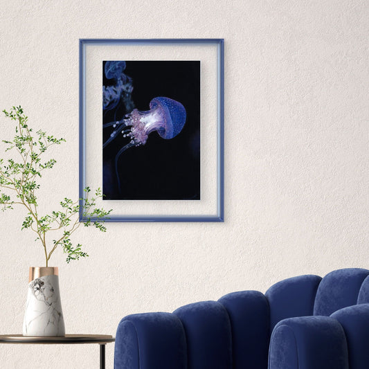 Buntstiftzeichnung einer blau lila schimmernden Qualle auf schwarzem Papier an der Wand über einem bläulichen Sessel und kleinem runden Tisch