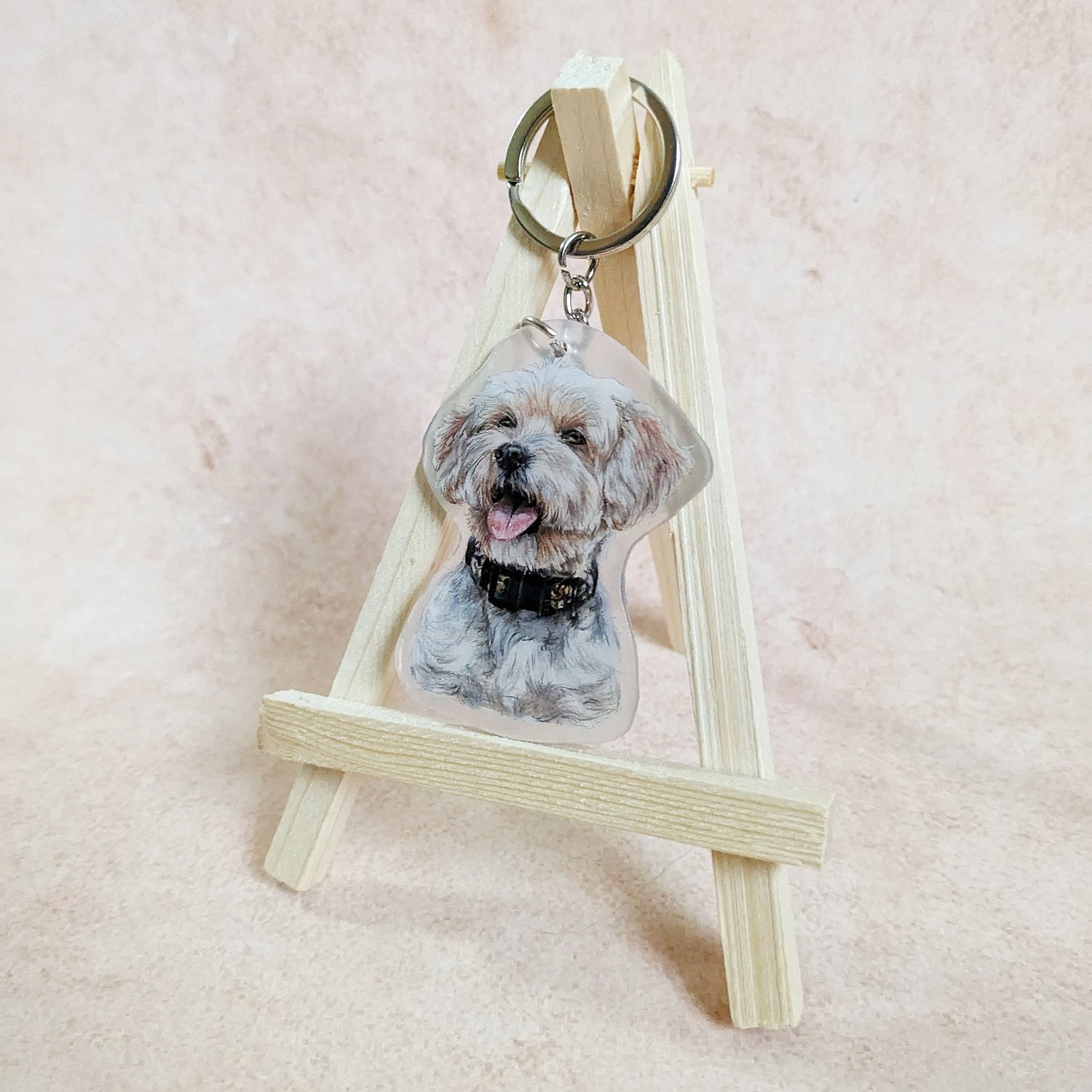 Gezeichnet Schlüsselanhänger eines wuscheligen weiß-beigen Hundes mit breitem schwarzen Halsband
